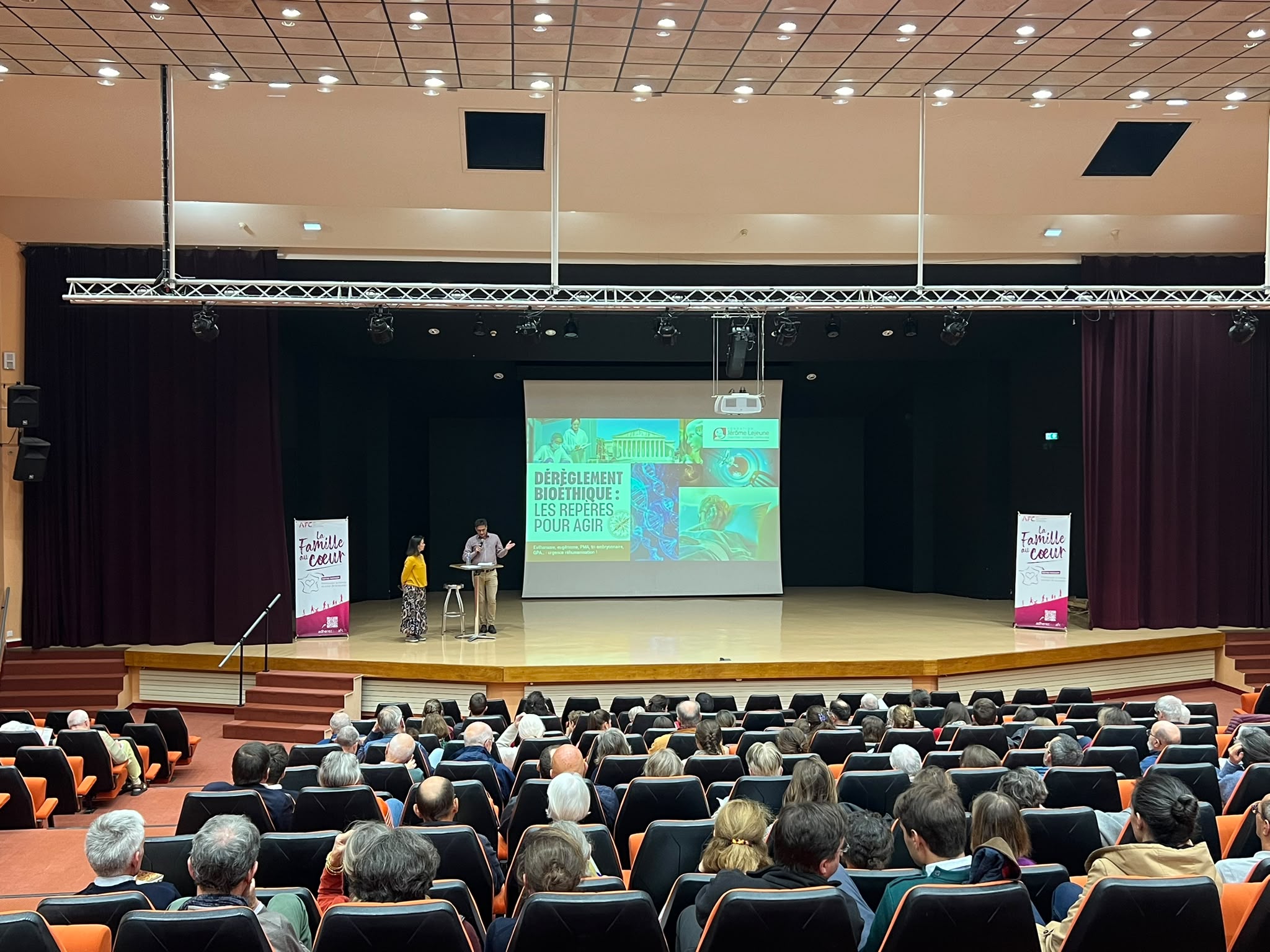 Scène de l’auditorium de l’Assomption à Rennes avec l’écran « Dérèglement bioéthique : les repères pour agir » et les kakémonos AFC